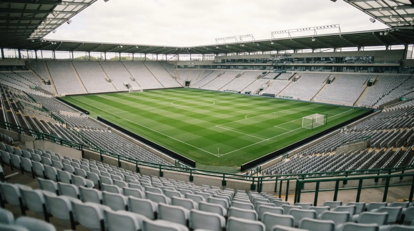 Ein leeres Fußballstadion bei Tageslicht von der Tribüne aus gesehen, der Rasen zeigt gleichmäßige Mähstreifen.