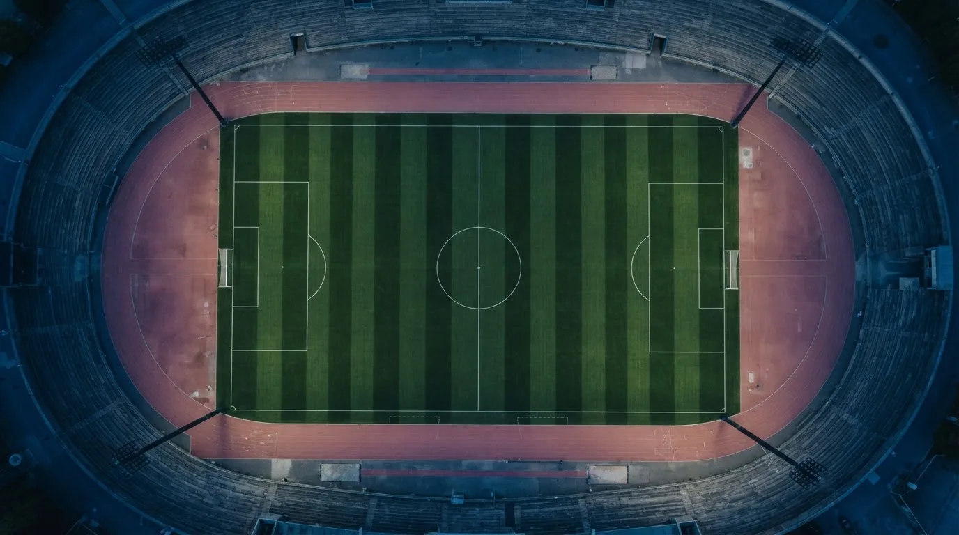 Ein Fußballplatz am Abend aus der Vogelperspektive, Flutlichtmasten ausgeschaltet, die Rasenlinien deutlich sichtbar.