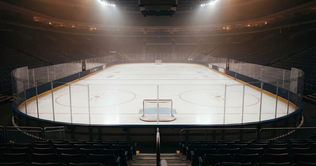 Eine Eishockeyhalle von der Tribüne aus gesehen, spiegelglatte Eisfläche, Banden ohne Schriftzüge, helles Flutlicht.